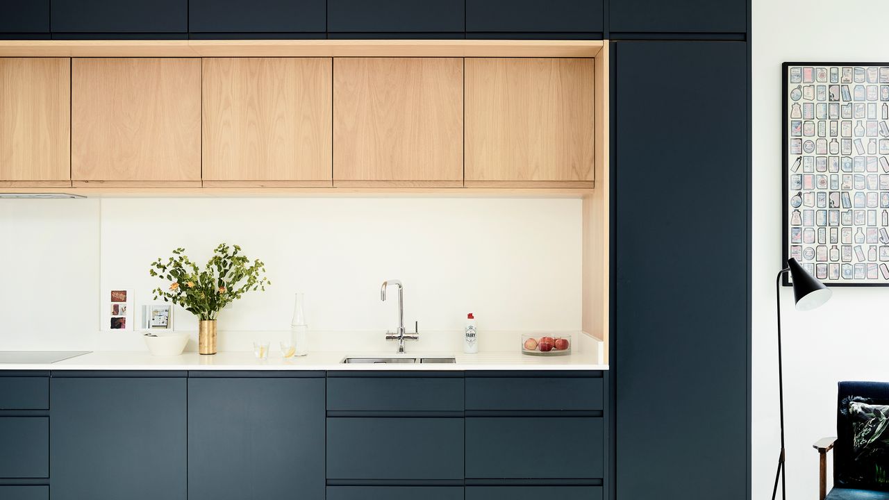 Kitchen with blue-green and wood cabinetry and white worktops