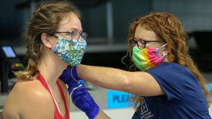 An NHS health worker administers a dose of Pfizer Covid-19 vaccine