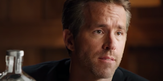 Ryan Reynolds is seated next to a bottle of Aviation American Gin in a commercial.