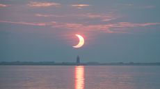 A partial solar eclipse is seen as the sun rises behind the Delaware Breakwater Lighthouse, Thursday, June 10, 2021, at Lewes Beach in Delaware. 