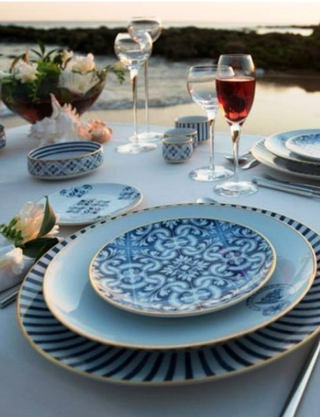 blue tile print plates sit on top of medium and large plates in a similar style on a set dinner table