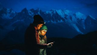 A couple examining a map wearing headlamps at night