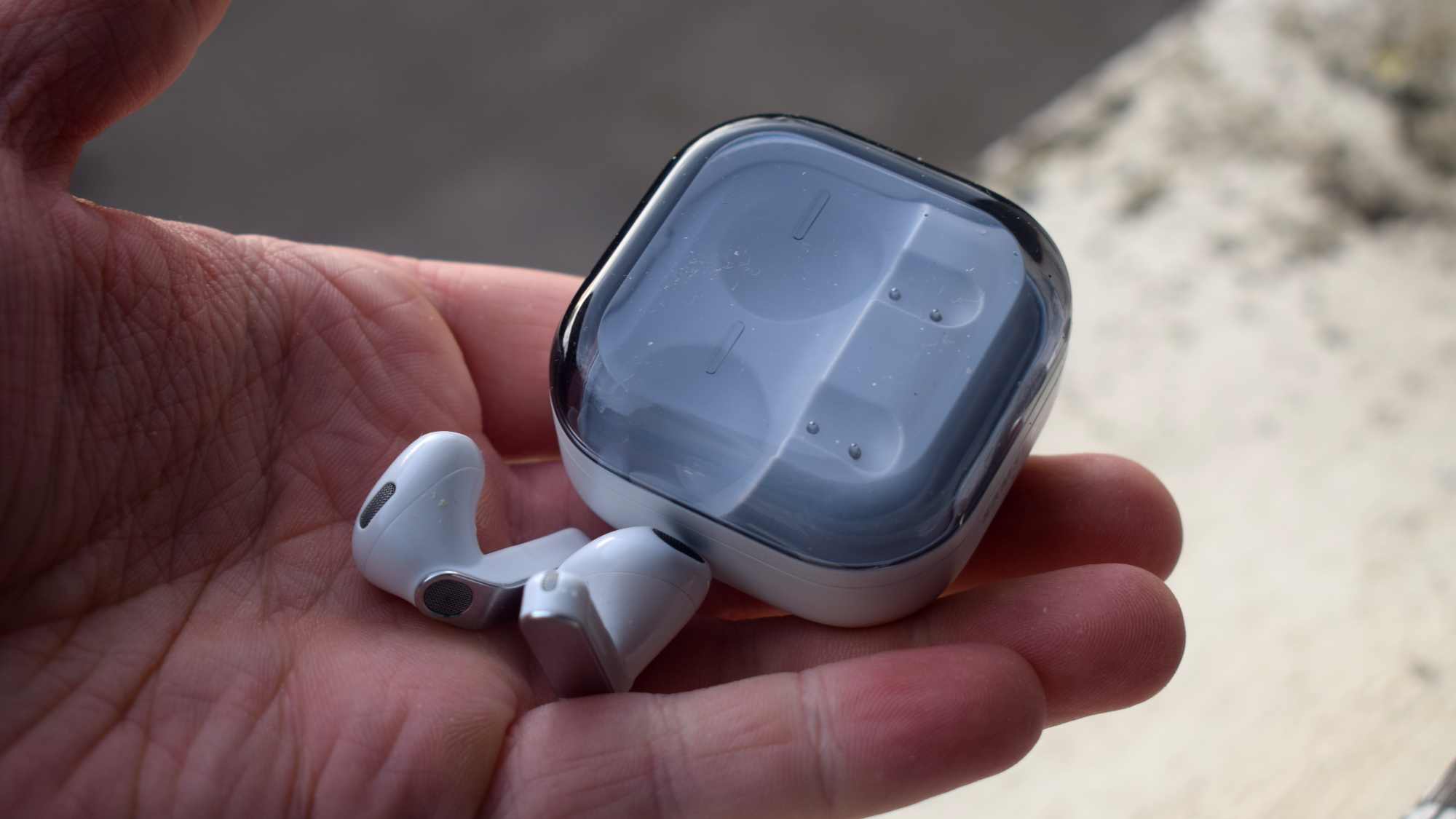 The Samsung Galaxy Buds 4 buds and case in a man's hand.