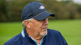 A golfer poses in the Johnnie-O Retro Logo Rope Performance Hat