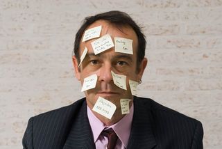 An isolated shot of a businessman with yellow sticky notes all over his face, which a has an expression that says, 'I forgot something.'