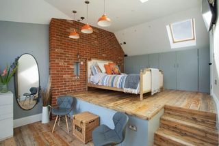 A bedroom in a loft conversion with a brick wall feature wall and blue walls
