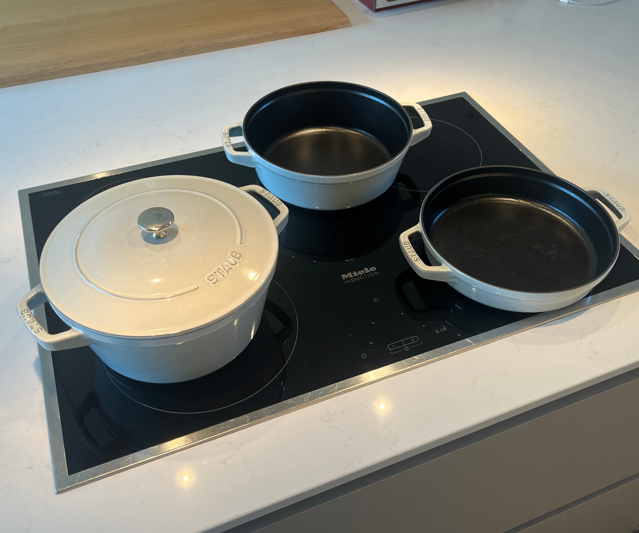 The three STAUB stackable pans unstacked on an electric stove top.