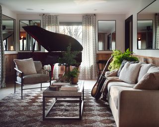 neutral living room with grand piano, neutral sofa and armchair, wooden coffee table and walls with mirrors
