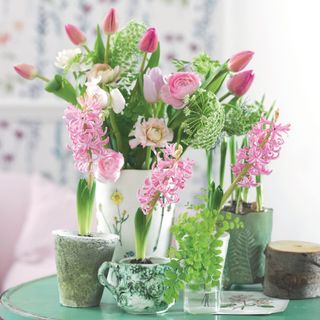 Cut flowers in white vase including pink tulips, roses and pink hyacinth