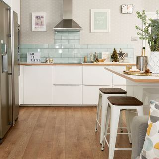 kitchen with brown floor tiles and wallpaper on wall white cabinets