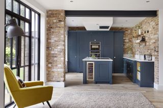 A traditional dark blue kitchen in an industrial warehouse with exposed bricks