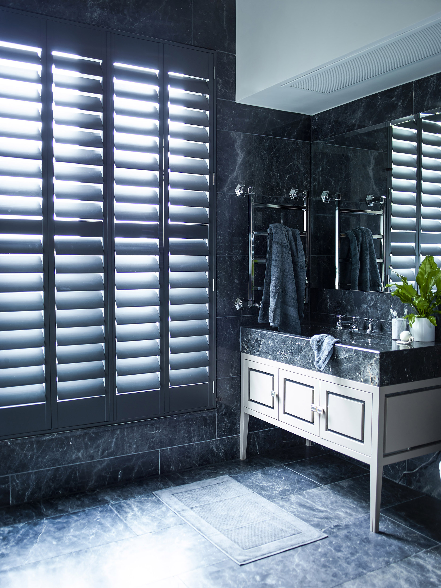 Black bathroom with marble floor and black shutters