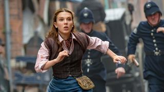 Millie Bobby Brown as Enola Holmes, running down the street in Enola Holmes 2, one of the Best family movies on Netflix