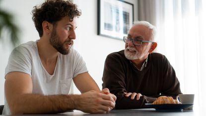 A father and son talk at the dining room table.