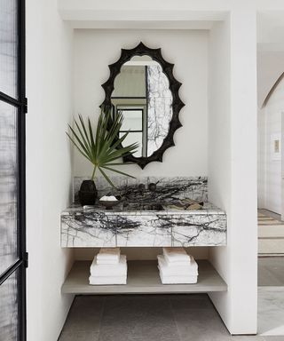 Bathroom vanity with striped marble counter and oval mirror