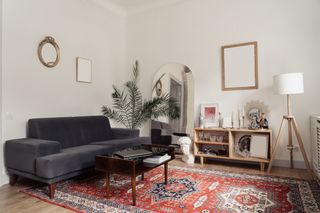 White small living room with large arched floor mirror red geometric rug
