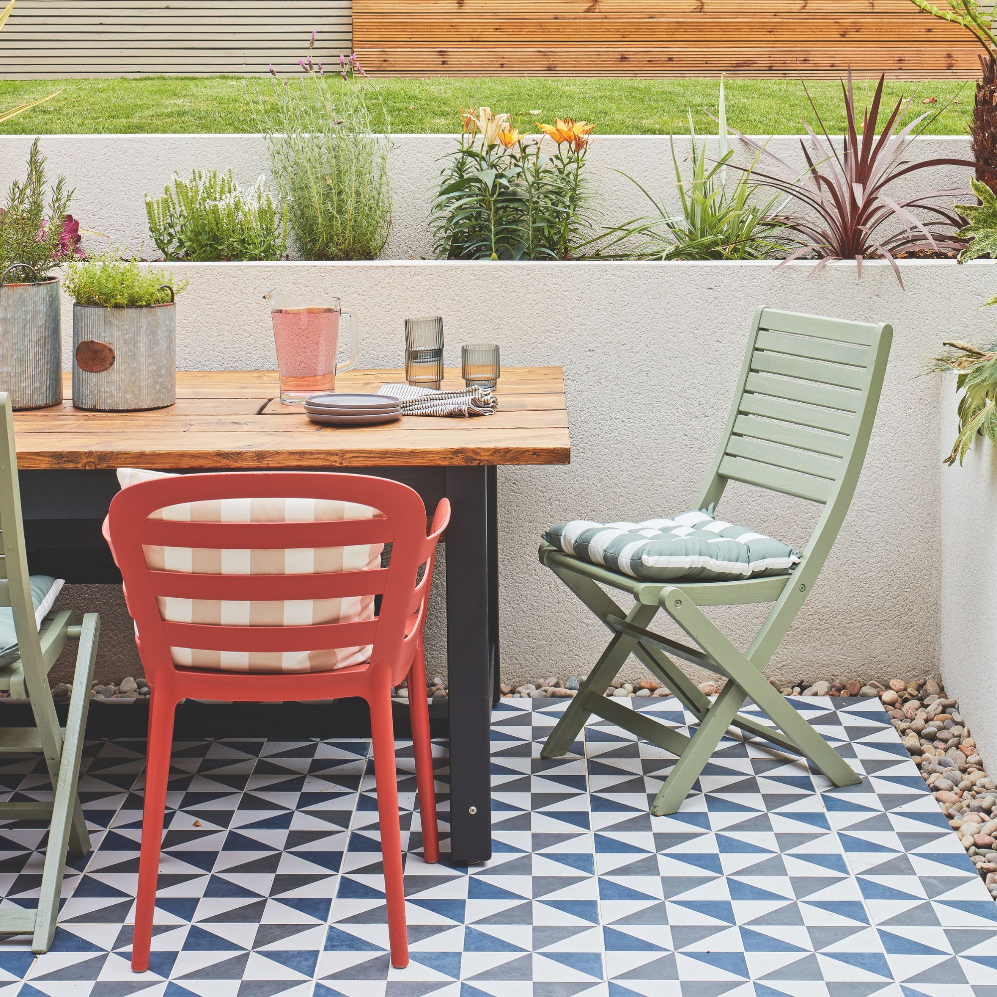 Garden patio area with a dining table and chairs, on top of a patterned rug