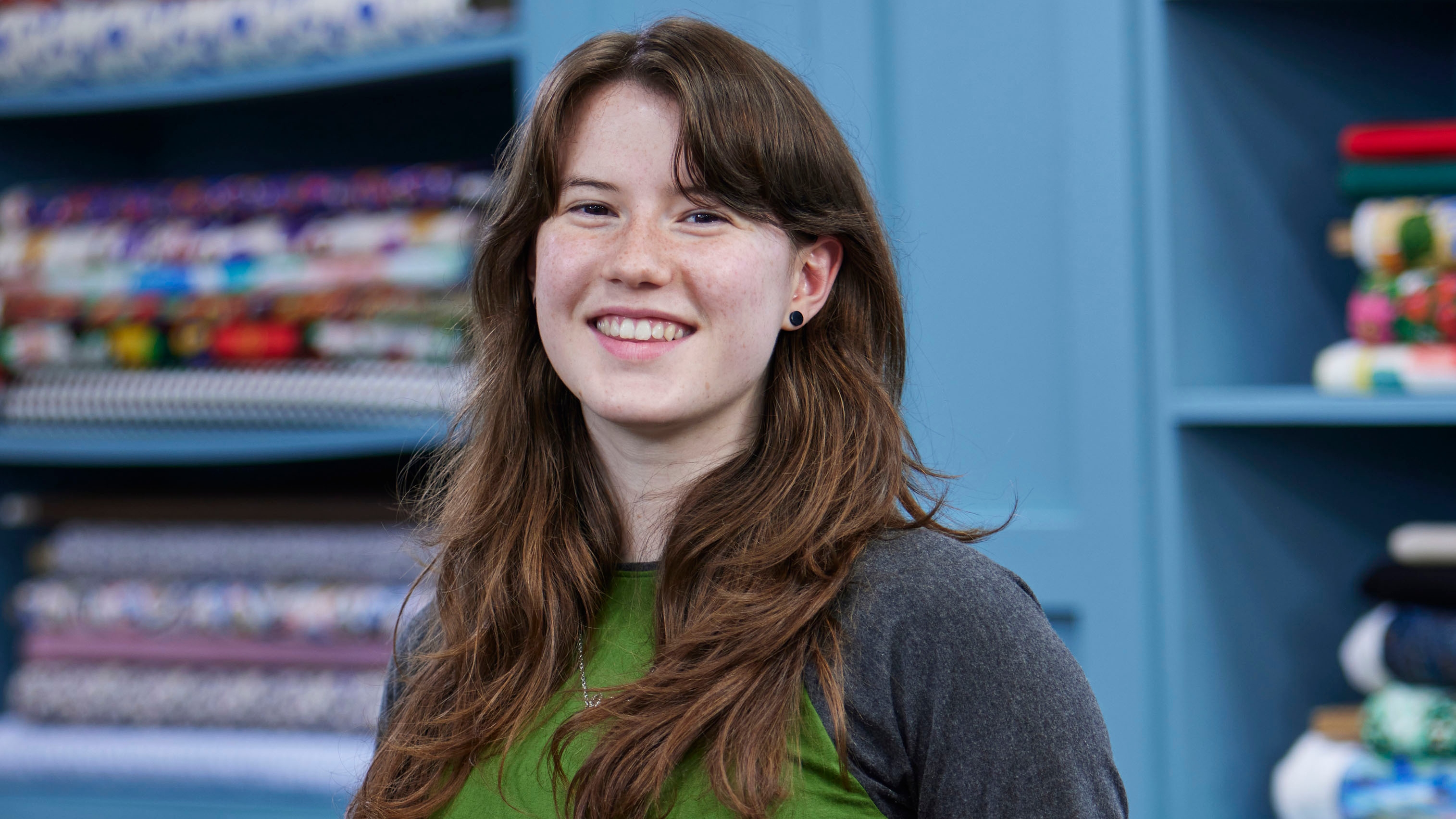Orla standing in the Great British Sewing Bee studio and smiling for the camera