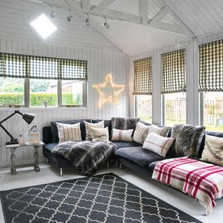 Living room with grey corner sofa and matching wooden wall and ceiling paneling