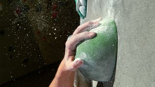 Detailed shot of a green sloper hold as unrecognizable climber grips it