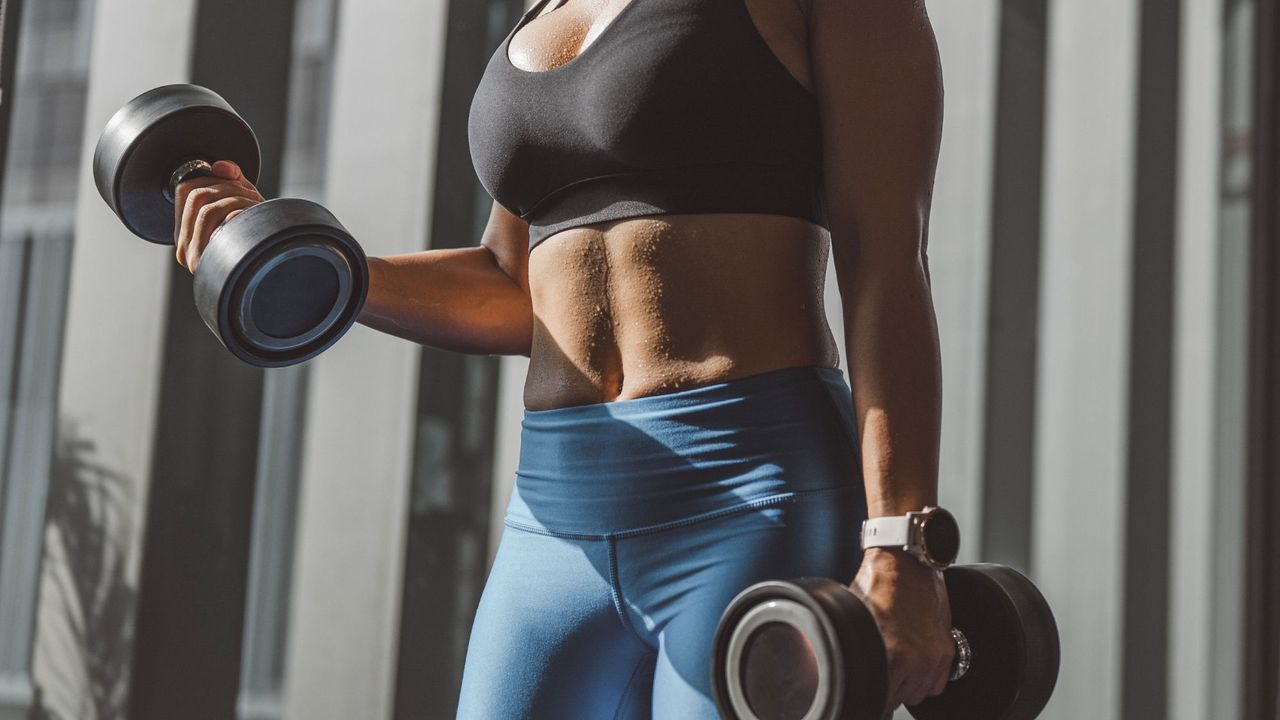 A woman doing EMOM workouts in the gym with weights