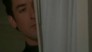 John Cusack peaking from behind a curtain in Grosse Pointe Blank