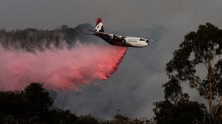 image of helicopter releasing flame retardant on Australian bushfire