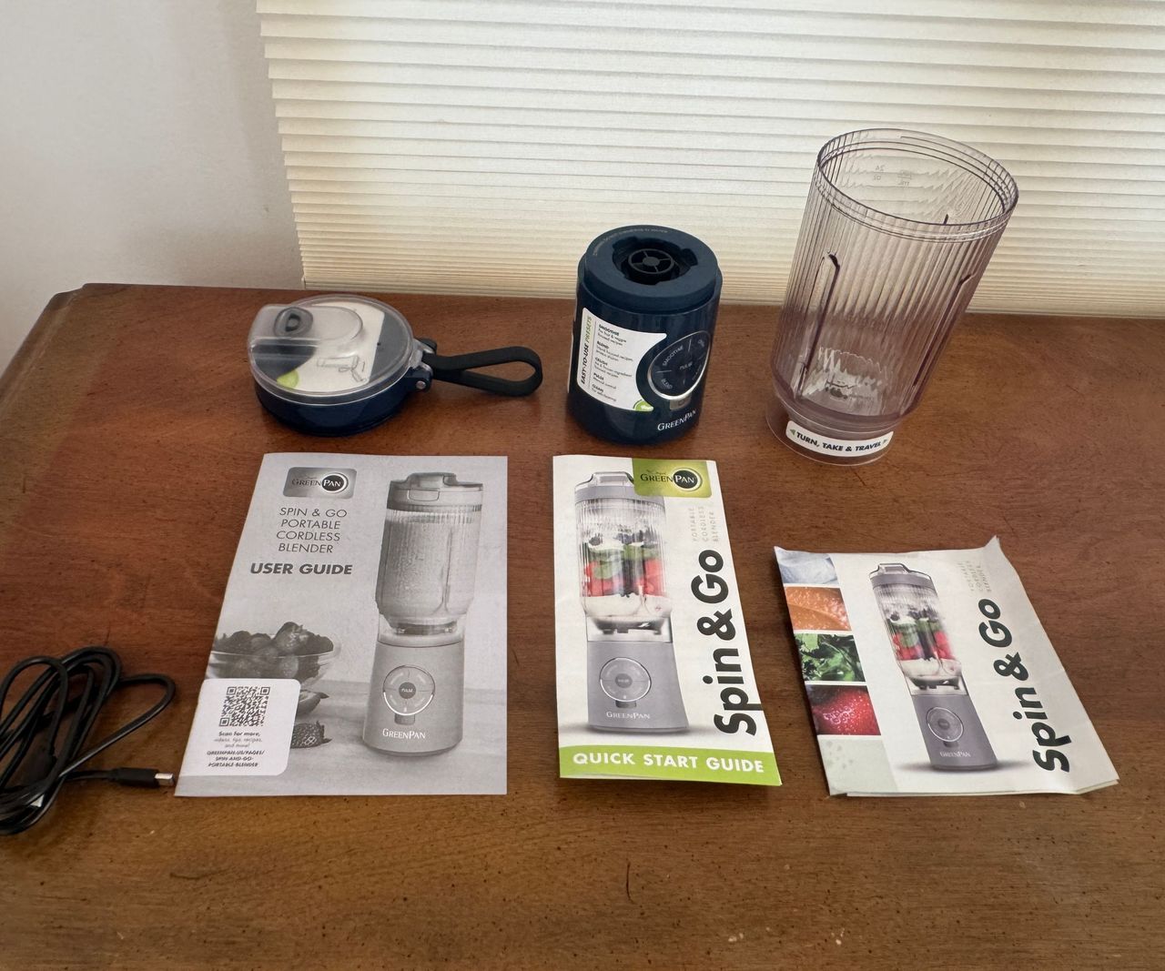 The GreenPan Spin &amp; Go instruction manuals laid out on a table with the dismantled blender behind it.