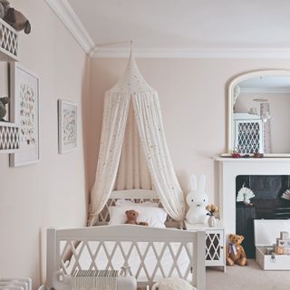 A neutral blush-coloured children's room with white furniture