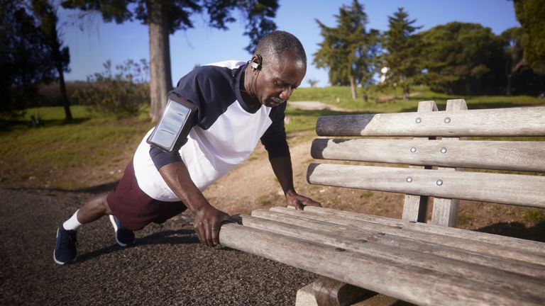 person doing push ups on a park bench