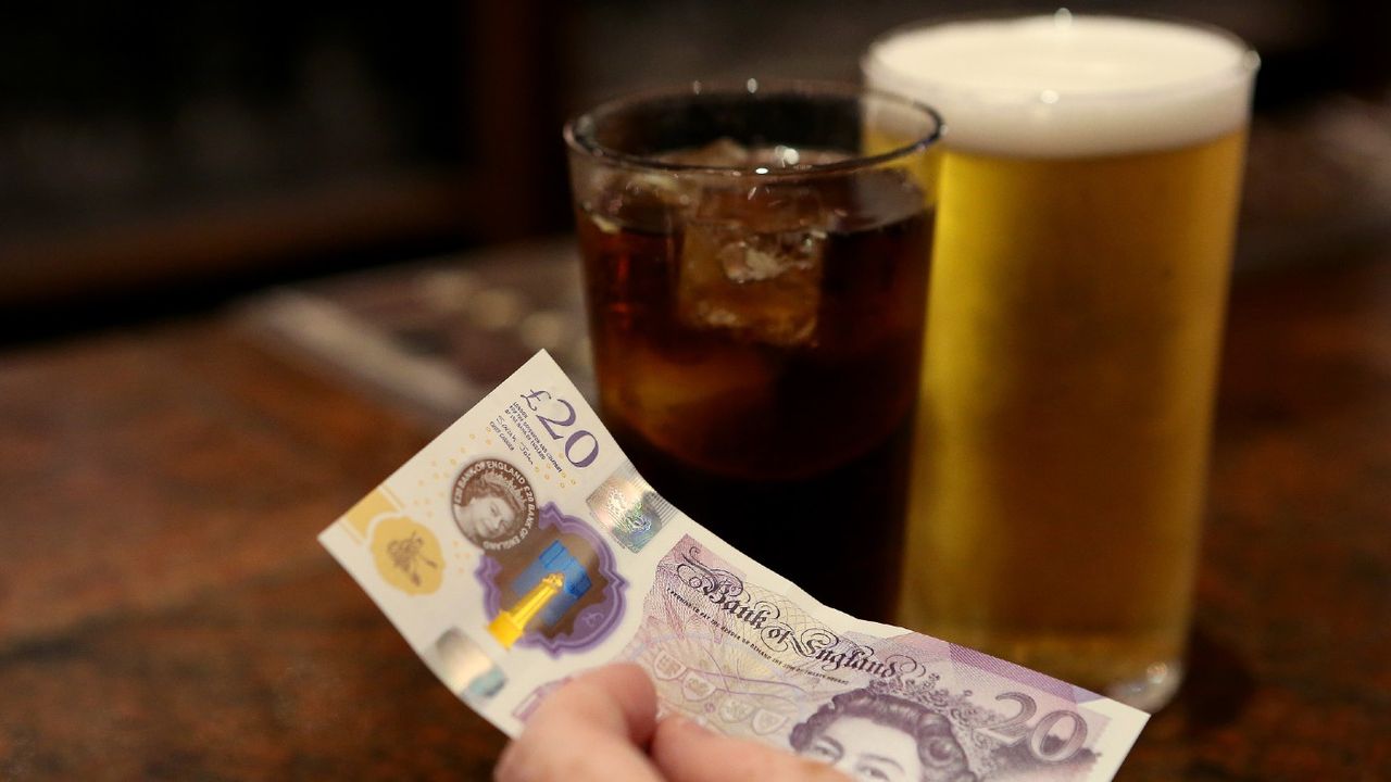 A customer pays for drinks at a pub using cash 