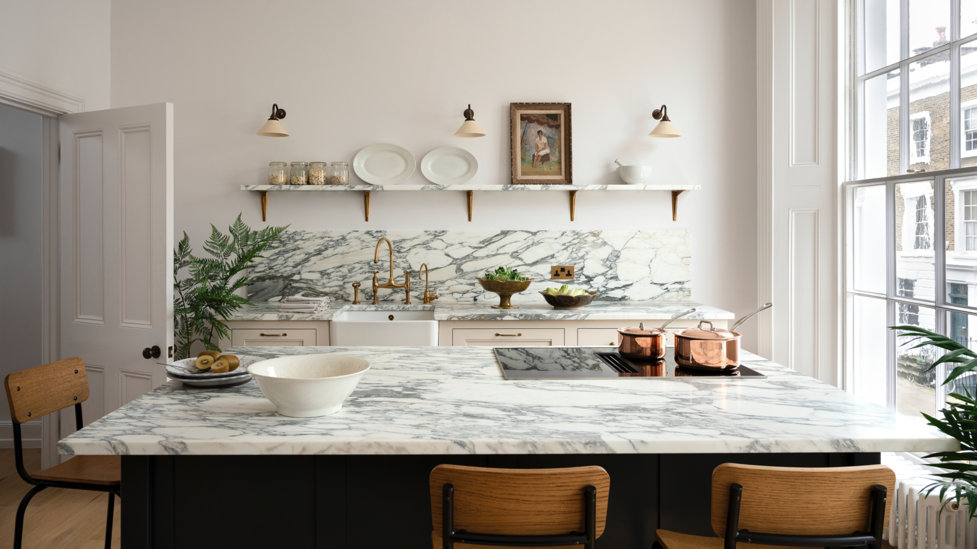 white and marble kitchen with open plan shelving, marble worktops, bar tools, copper accessories