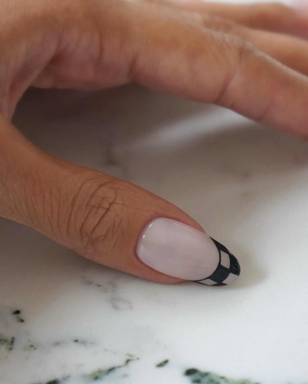 A French manicure with checkered print tips by Iram Shelton