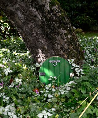 painted wooden fairy door at the base of a tree