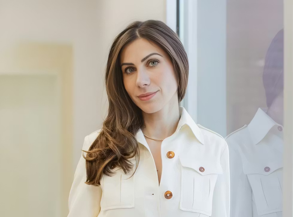 a white woman in a white coat with gold buttons and brown hair