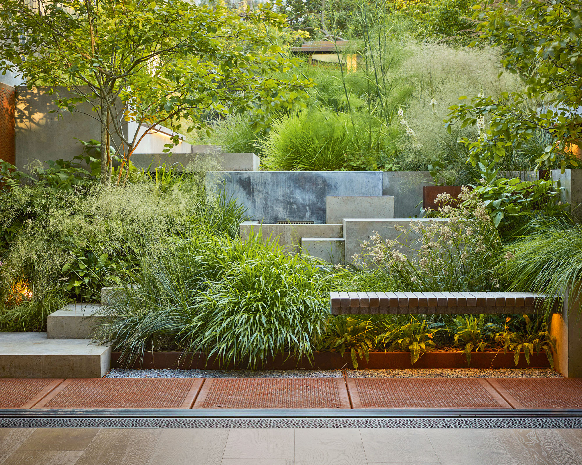 Large green garden with concrete steps, wooden bench