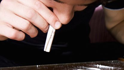 A young man sniffs cocaine