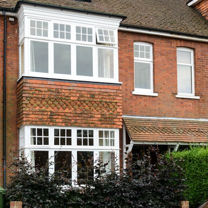 brick wall with white window and trees