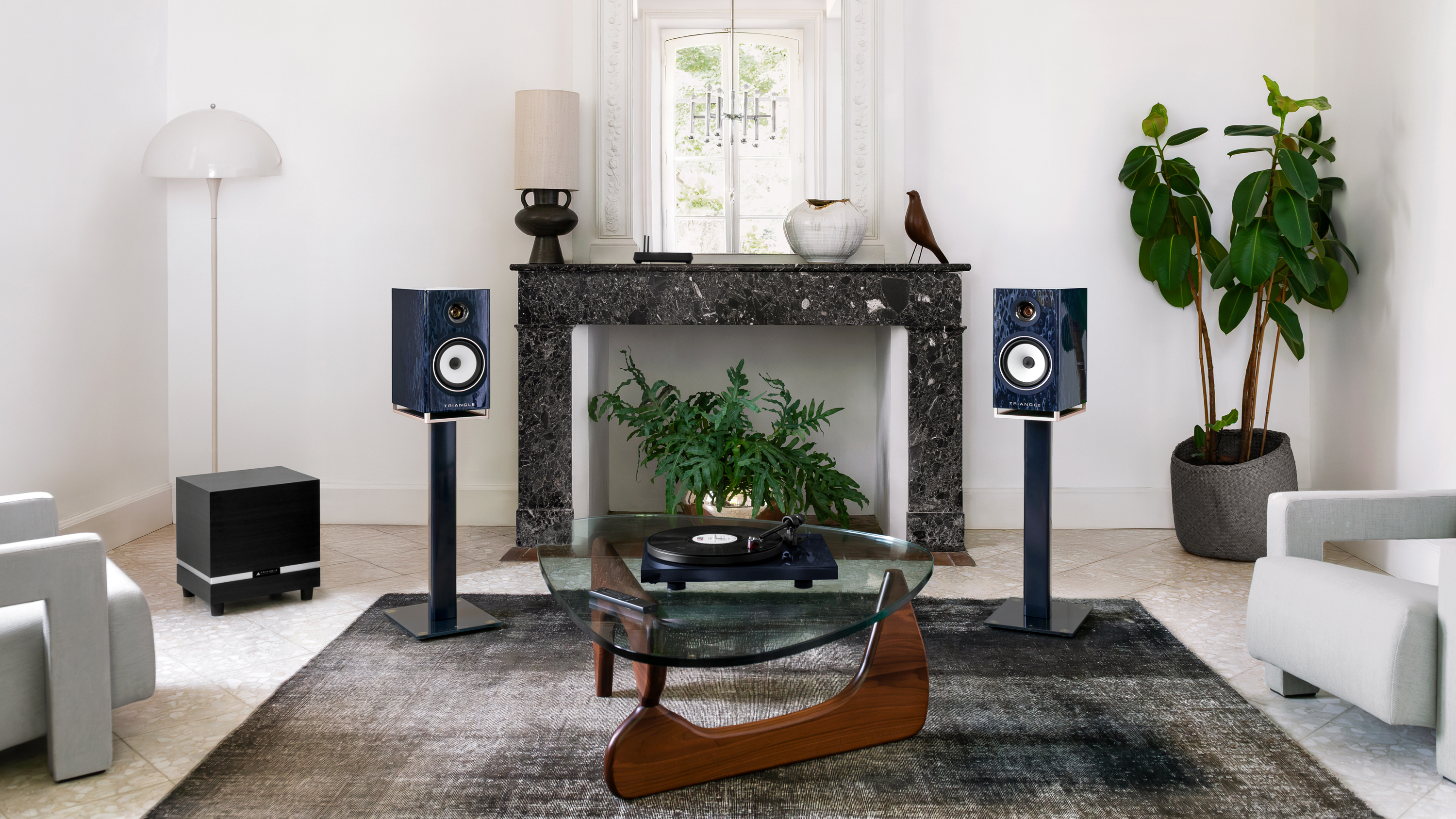 The triangle capella 2 speakers pictured on stands in a beautifully decorated black and white living room