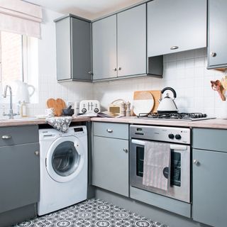 blue kitchen with oven, washing machine and kettle