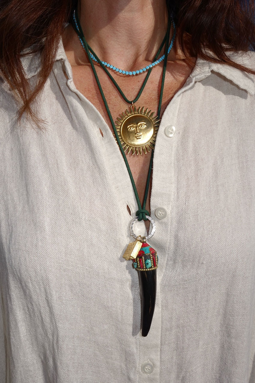 a woman wearing a sun pendant necklace stack and a white button-down shirt