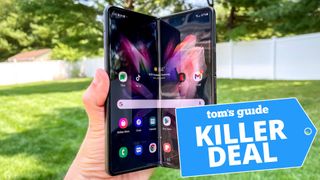A photo of a person holding a Samsung Galaxy Z Fold 3 phone with the "Tom's Guide killer deal" tag overlaid