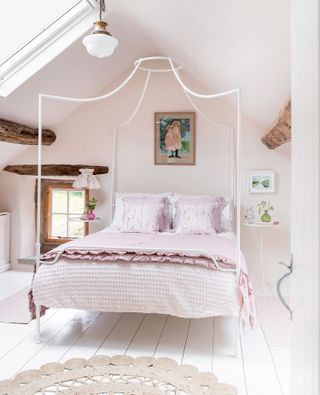 bedroom with pink walls and modern white four poster bed with pink bedlinen