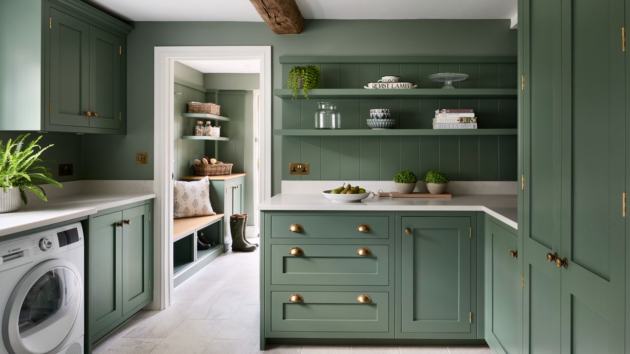 a large green laundry room with cabinetry, floating shelves, a washing machine, and an entryway in the background