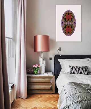 Bedroom with pretty coving, parquet flooring and a double bed with white bedding, bedside table with white lamp and pink shade.