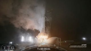 a black-and-white spacex falcon 9 rocket launches into a night sky.