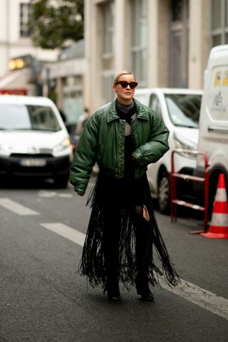 woman wearing puffer jacket, fringed dress, and boots