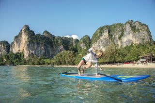 Happy boy paddling on stand up paddle board in Ao nang, Krabi, Thailand.