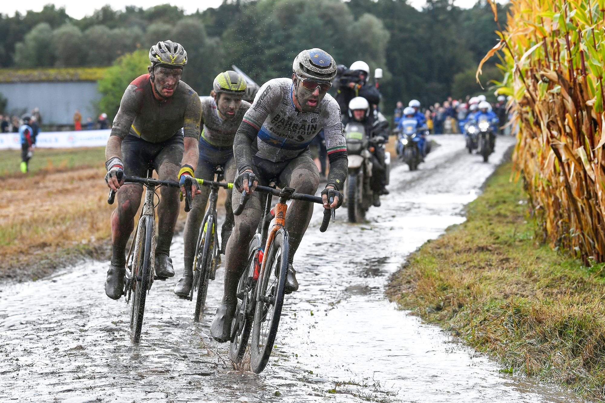 A mud-caked Sonny Colbrelli (Bahrain Victorious) leads a group over a wet cobbled sector en route to victory at the 2021 Paris-Roubaix
