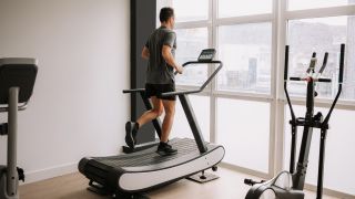 Man running on self-powered treadmill, which has a curved running belt